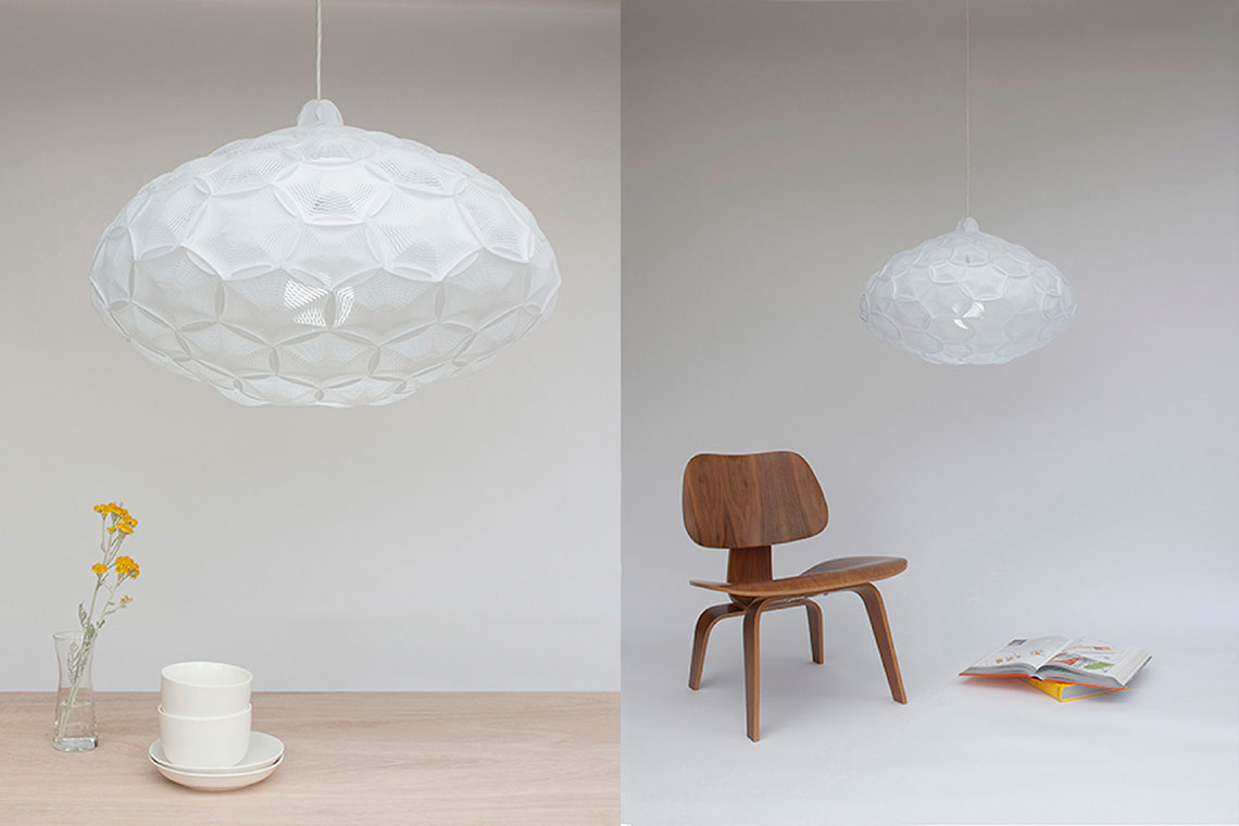 Airy Large cloud-like pendant lamp hung over a wood dining table and Airy Large pendant light shown with wood Eames chair and an open book