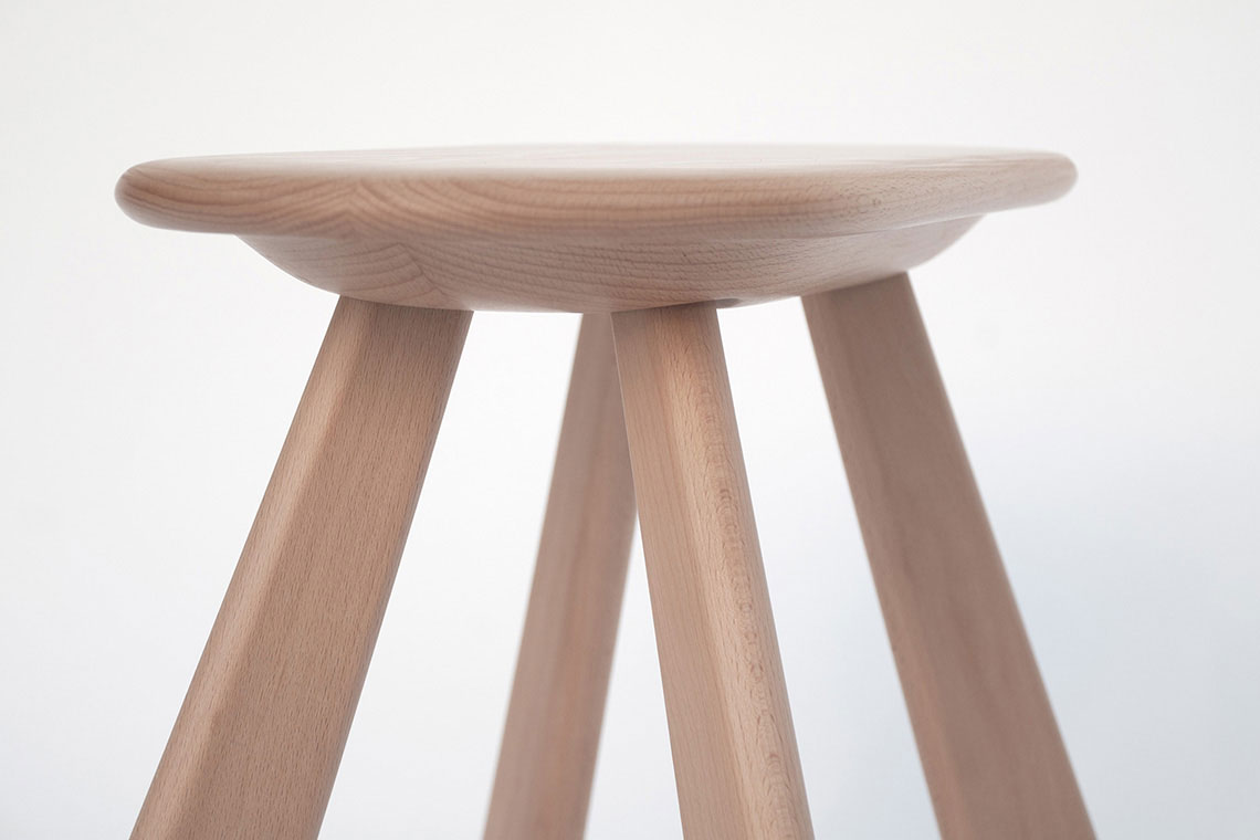 Atlas wood stool seat detail showing continuous under the seat ledge with a grip area for ease of moving a stool around; gentle seat underbelly creates a depth for traditional method of leg insertion