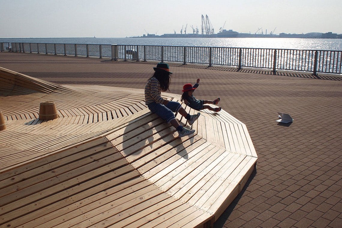 24d-studio designed Crater Lake installation platform is used as a wood slide by a laughing family