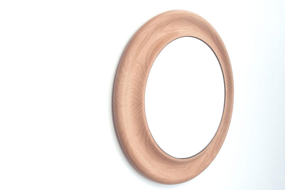 Crater Mirror encased in sculptural wood frame is a play with asymmetrically nested circles and inspired by the Moon Craters; shown in small size 35 cm in diameter.