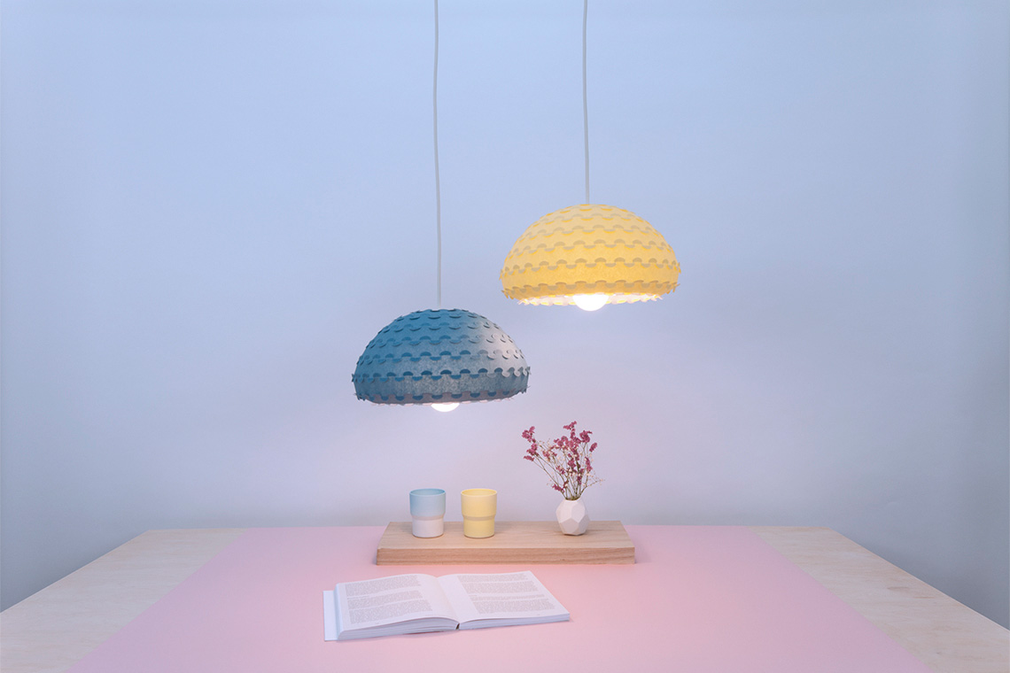 Voluminous and bright two kasa ceiling lamps in yellow and blue over a table create a sunny and cozy environment.